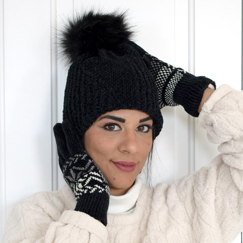 Women's Chenille Hat with Faux Fur Pom in Black on Figure. Model standing in front of a door with snowflake gloves.