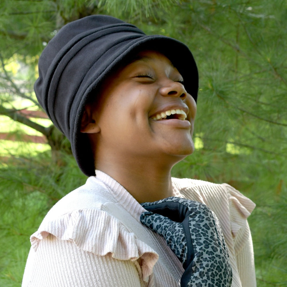 Women's Lined Recycled Fleece Water Repellent Cloche Hat in Black on Figure. Model wearing hat and Isotoner Chevron Gloves laughing