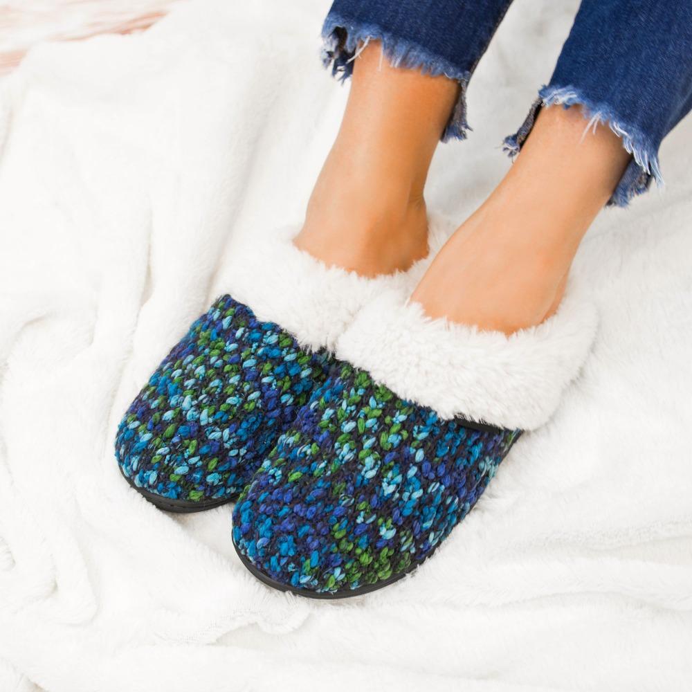 Women's Sweater Knit Amanda Hoodback Slippers in Navy Blue with green on Model laying in blankets