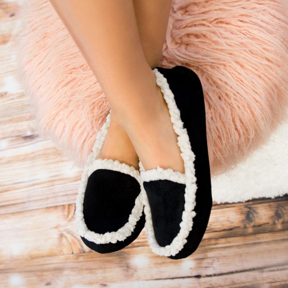 Women's Microsuede Alex Moccasin Slippers in Black On Model Feet propped up on stool