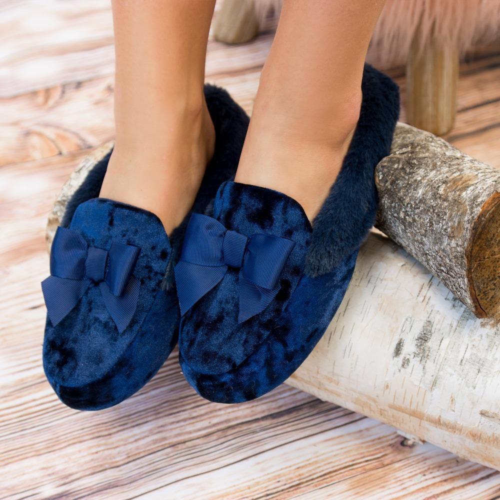 Women's Iridescent Velour Krista Hoodback Slippers in Navy Blue on Model Slippers resting on logs