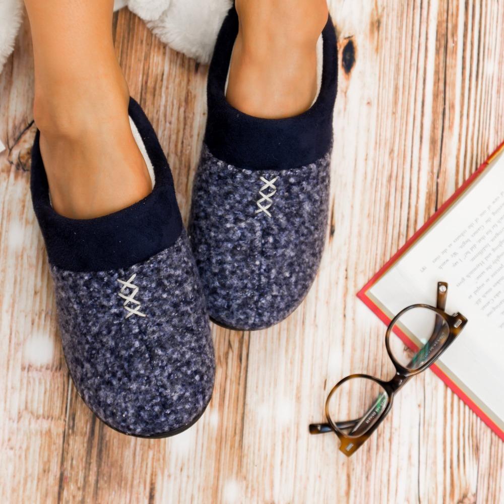 Women's Heathered Knit Jessie Hoodback Slippers in Navy Blue on Model reading  on hardwood floor